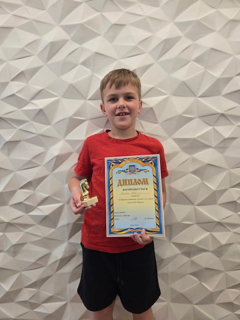 Young boy in red shirt holding certificate and medal against textured geometric wall background